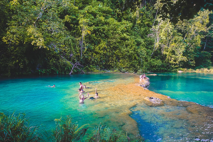 The blue waters of Semuc Champey in Guatemala with people swimming